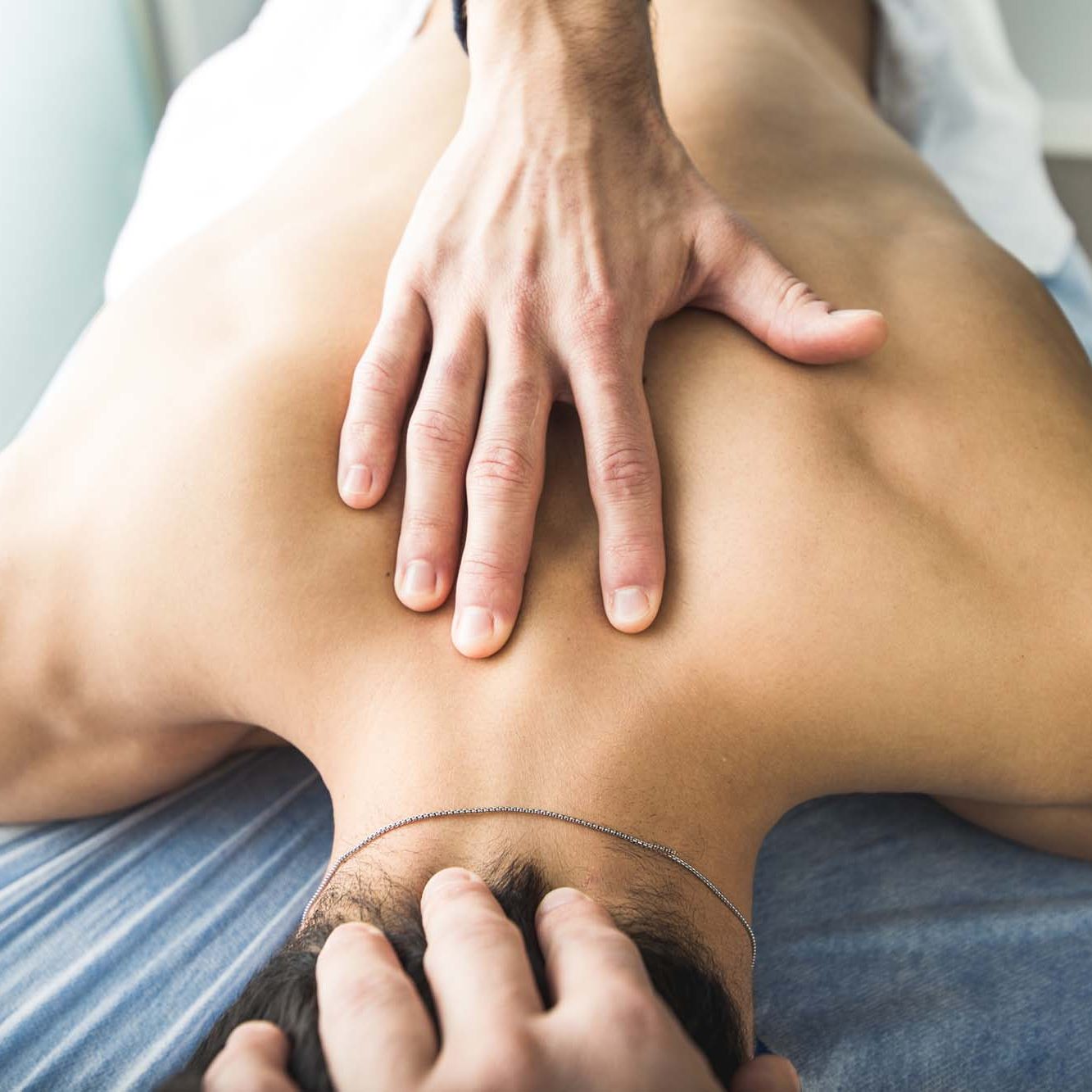 Physiotherapist massaging the back and neck of a young man. Concept of physiotherapy